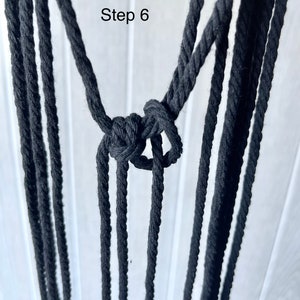 May include: Step 6 of a macrame project, showing a knot tied with black cord.