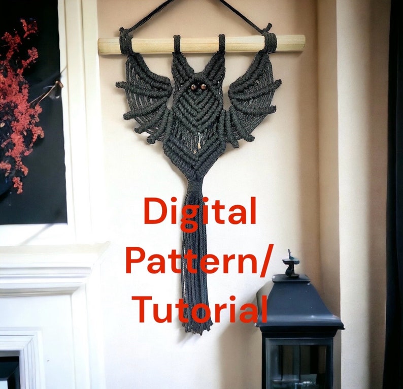 May include: A black macrame bat wall hanging with a long tassel. The text "Digital Pattern/Tutorial" is written in red below the bat.