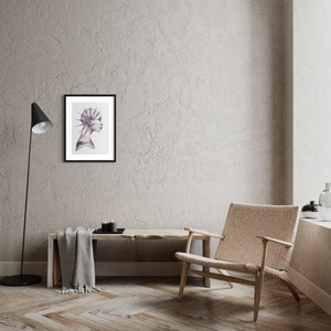 May include: A framed illustration of a person's profile with a detailed, spiky design on their head. The background is a light gray wall with a wooden floor.