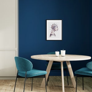 May include: A round wooden table with a blue and white watercolor print of a woman with a spiky hairdo hanging on the wall behind it. Two teal chairs are placed on either side of the table.