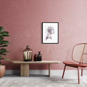 May include: A framed print of a watercolor illustration of a woman's profile with a crown of thorns on her head. The print is hanging on a pink wall in a room with a chair and a plant.
