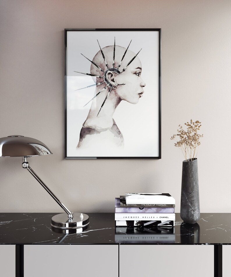 May include: A black framed print of a watercolor painting of a person with a spiky, geometric design on their head. The person is looking to the right. The print is hanging on a light beige wall above a black marble table with a silver lamp and a vase with dried flowers.