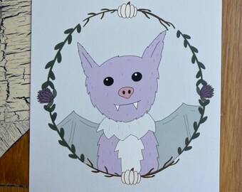 May include: A purple bat with white fur around its neck is surrounded by a wreath of green leaves and white pumpkins. The bat has a pink nose and black eyes.