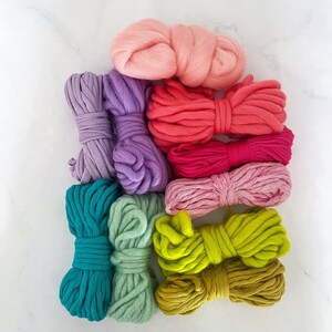 May include: A set of eight colorful yarn skeins in various shades of pink, purple, teal, green, and yellow. The yarn is arranged in a stack, with the pink skein on top.
