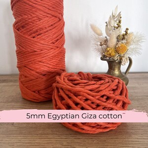 Può includere: Un primo piano di un rotolo di corda di cotone arancione da 5 mm di spessore. La corda è realizzata in cotone egiziano Giza.