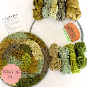 May include: A weaving kit with a circular woven piece in shades of green and brown, surrounded by bundles of yarn in various green hues. A wooden comb and a printed instruction sheet are also included. The text "Lush Little Loops" is visible.