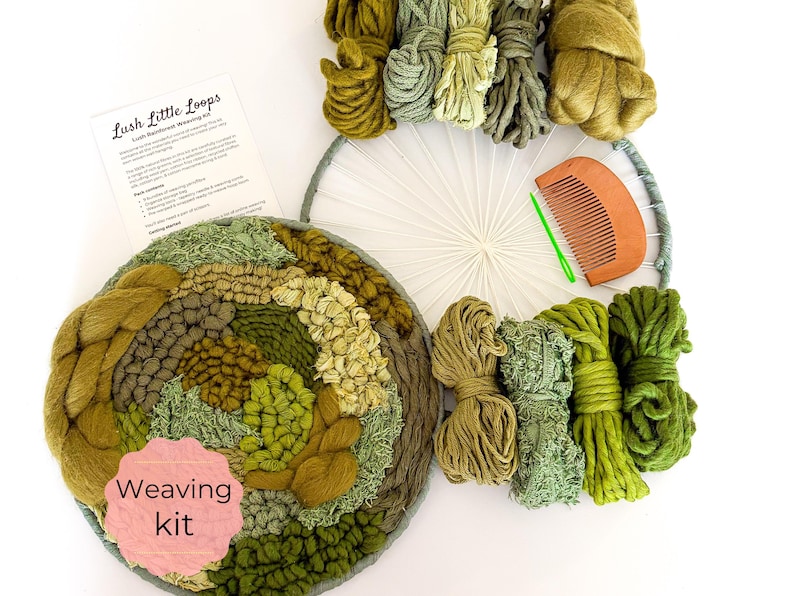 May include: A weaving kit with a circular woven piece in shades of green and brown, surrounded by bundles of yarn in various green hues. A wooden comb and a printed instruction sheet are also included. The text "Lush Little Loops" is visible.