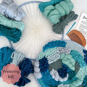 May include: A weaving kit with a wooden loom, yarn in shades of blue and green, a wooden comb, and a needle. The kit includes instructions for creating a wall hanging. The text on the instructions reads "Lush Little Loops -  Round Wall Weaving Kit".