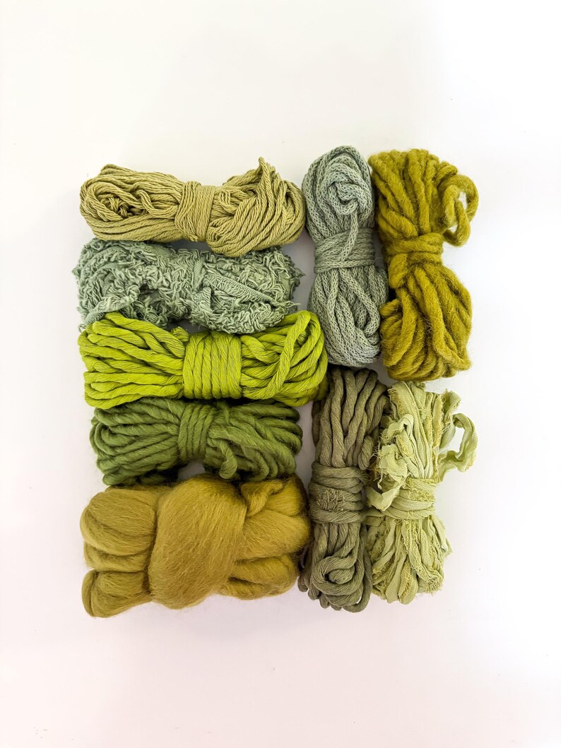 May include: An assortment of green yarn bundles in various shades, from light olive to deep forest green. The yarn textures vary, including smooth, textured, and fluffy, arranged on a white background. Ideal for crafting and textile projects.