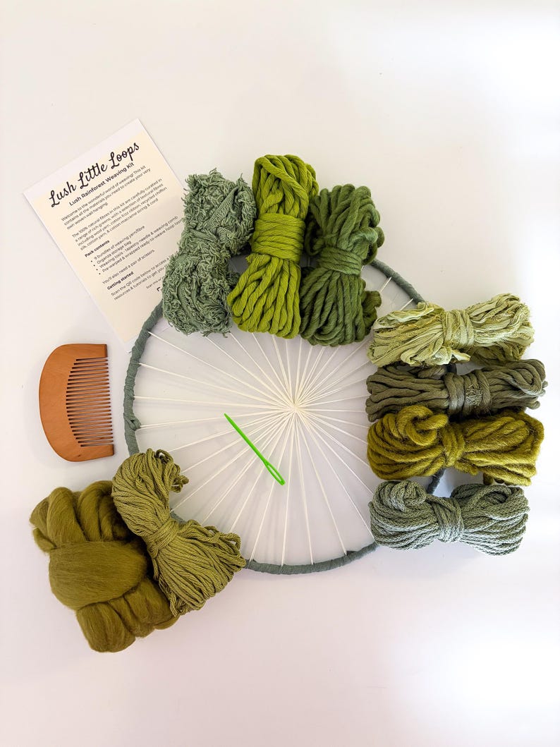 May include: A Lush Little Loops weaving kit with various shades of green yarn, a wooden comb, a weaving needle, and a circular loom. The kit includes a printed instruction sheet. The yarn colors range from light to dark green.