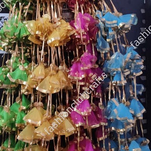 May include: A collection of colorful, sheer fabric tassels with gold trim. The tassels are arranged in rows and are hanging from a string. The tassels are in shades of green, yellow, pink, and blue.