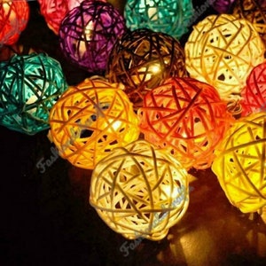 Puede incluir: Cadena de luces con cubiertas de luz de forma de bola tejidas de colores. Las luces están enhebradas con un cable transparente. Las bolas son de varios colores, incluyendo azul verdoso, morado, amarillo, naranja y blanco.