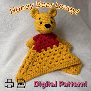 Op de afbeelding: Een gehaakte gele beer lovey met een rode kraag en een gele deken. De tekst "Honey Bear Lovey!" en "Digital Pattern!" worden op de afbeelding weergegeven. Het PDF-pictogram is ook zichtbaar.