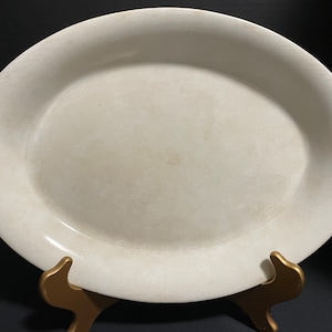 May include: A large, oval, white ceramic serving platter with a slightly textured surface.