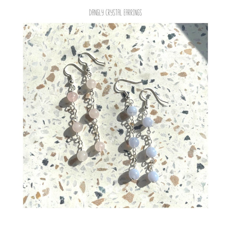 May include: A pair of dangle earrings with silver chains and light pink and light blue crystal beads.