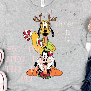 May include: A gray t-shirt with a cartoon image of Pluto and Goofy wearing Santa hats. The text "SVG PNG JPEG EPS TIFF PDF" is printed on the shirt.