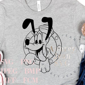 以下が含まれることがあります： グレーのTシャツに、セーラーハットをかぶった犬の白黒の漫画の画像がプリントされています。犬は「Ahoy」と「Grey Jeans」の文字が書かれた円の中にいます。Tシャツは、白いスニーカー、青いジーンズ、金色のグリッターのミッキーマウスの耳と一緒に白い表面に置かれています。