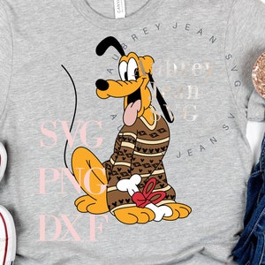 May include: A gray t-shirt with a cartoon image of Pluto wearing a brown and red sweater. The text "ABREY JEAN SVG PNG DXF" is printed in a circle around Pluto.