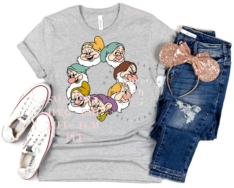 K&ouml;nnte beinhalten: Ein graues T-Shirt mit einem Kreis aus sieben Zwergen aus dem Disney-Film Schneewittchen. Die Zwerge sind in einem Kreis angeordnet, mit ihren Namen darum herum. Das T-Shirt liegt auf einem wei&szlig;en Hintergrund mit einem Paar wei&szlig;en Turnschuhen, einer blauen Jeans und einem Paar goldenen Glitzer-Minnie-Maus-Ohren.