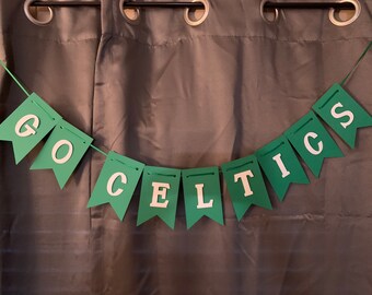 May include: Green and white banner with the text "GO CELTICS" hanging on a gray curtain.