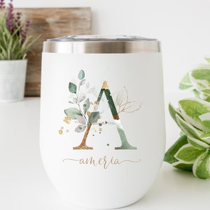 May include: White stainless steel tumbler with a gold and green floral design and the letter "A" in the centre. The name "amaria" is written in cursive below the design.