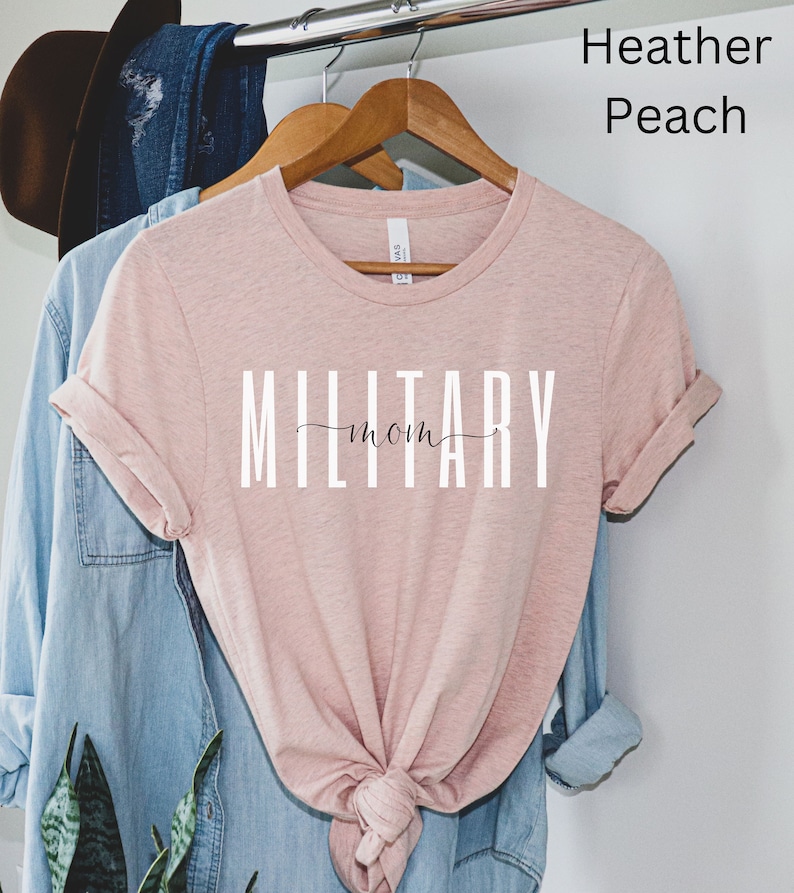 Pode incluir: Uma camiseta cor p&ecirc;ssego com o texto "MILITARY mom" em letras brancas.