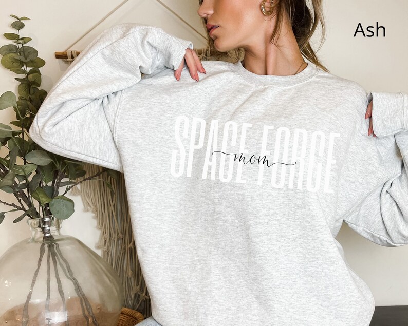 Puede incluir: Sudadera gris ceniza con el texto "Space Force Mom" impreso en blanco.