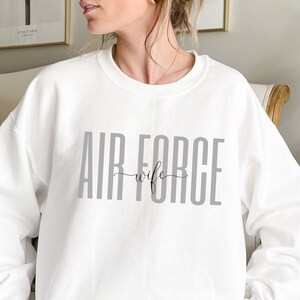 May include: White sweatshirt with the text "AIR FORCE wife" in gray letters.