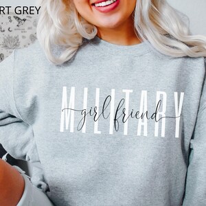 K&ouml;nnte beinhalten: Ein graues Sweatshirt mit dem Aufdruck "MILITARY girlfriend" in Wei&szlig;.