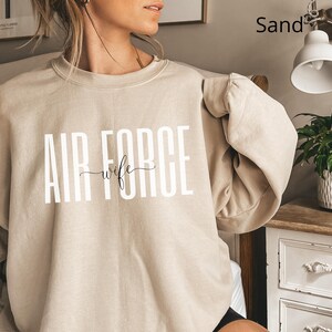 May include: A sand-colored sweatshirt with the text "AIR FORCE wife" printed in white on the front.