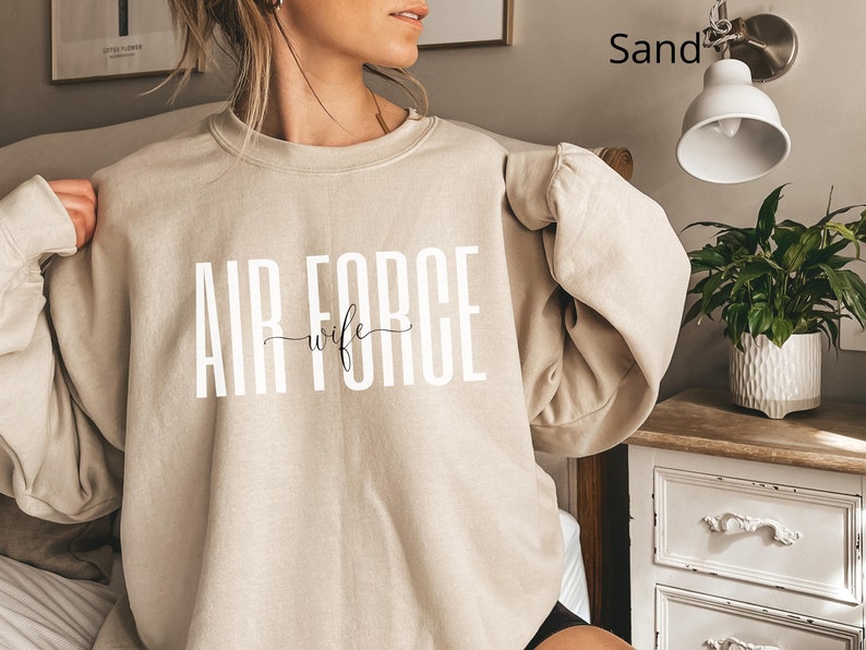 May include: A sand-colored sweatshirt with the text "AIR FORCE wife" printed in white on the front.