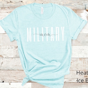 Pode incluir: Uma camiseta azul clara com o texto "Military mom" em letras brancas. A camiseta &eacute; feita de um material macio e confort&aacute;vel.