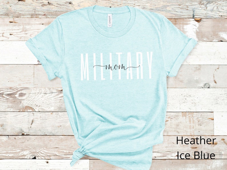 Pode incluir: Uma camiseta azul clara com o texto "Military mom" em letras brancas. A camiseta &eacute; feita de um material macio e confort&aacute;vel.