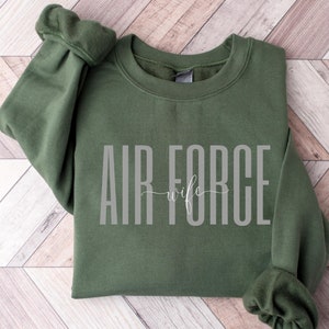 May include: A green sweatshirt with the text "AIR FORCE wife" in white lettering.