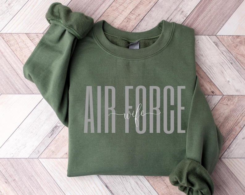 May include: A green sweatshirt with the text "AIR FORCE wife" in white lettering.