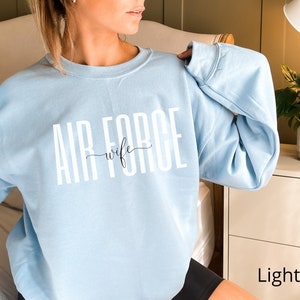 May include: Light blue sweatshirt with the text "AIR FORCE wife" in white lettering.