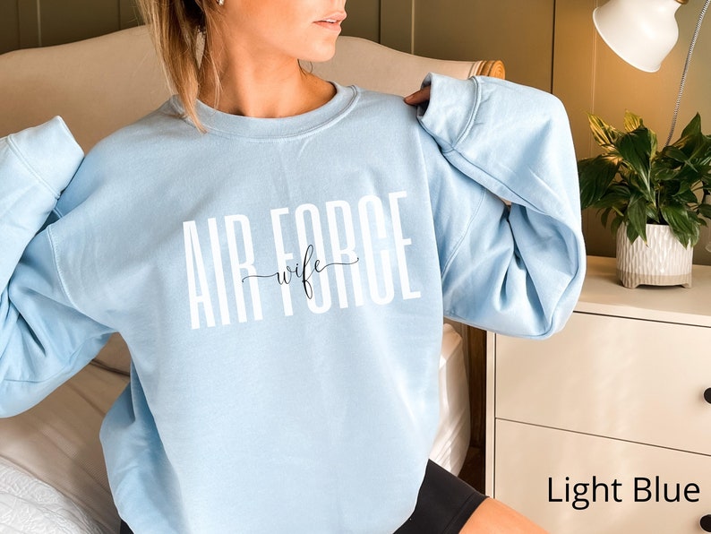May include: Light blue sweatshirt with the text "AIR FORCE wife" in white lettering.
