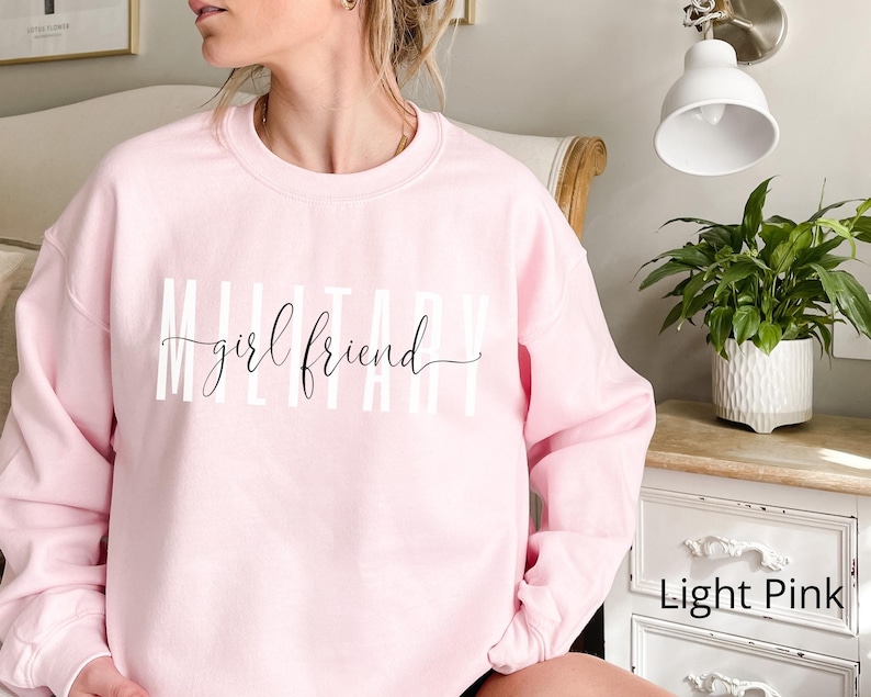 K&ouml;nnte beinhalten: Hellrosafarbener Pullover mit dem Schriftzug "Military girlfriend" in wei&szlig;.