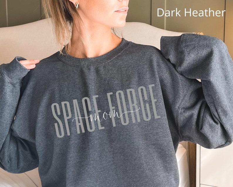 Puede incluir: Sudadera gris oscuro jaspeado con el texto "SPACE FORCE mom" en letras blancas.
