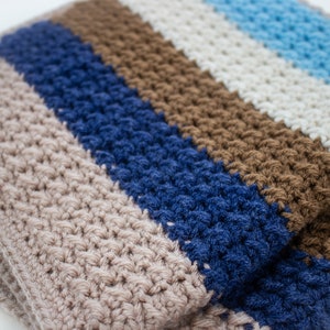 May include: A striped crocheted blanket in shades of brown, beige, blue, and light blue.
