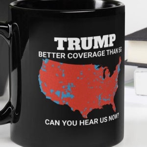 Puede incluir: Taza de café negra con un gráfico blanco de un mapa de los Estados Unidos con marcas rojas y azules. El texto "TRUMP BETTER COVERAGE THAN 5G CAN YOU HEAR US NOW?" está impreso en la taza.