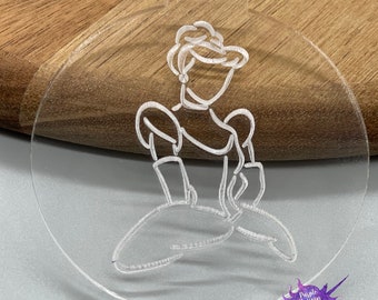 May include: A clear acrylic ornament with an etched outline of a woman in a ball gown. The design is delicately etched into the clear surface. The ornament has a small rectangular tab at the top for hanging, and a circular shape.