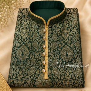 Può includere: Un kurta verde scuro con un intricato motivo floreale in broccato color oro, un colletto alla coreana con profili dorati e un'abbottonatura centrale con sei bottoni trasparenti effetto cristallo. Il testo ThelehengaCloset è in basso a destra.