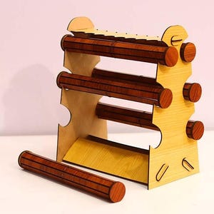 May include: Wooden jewellery organiser with three rotating rods for storing bracelets and bangles. The organiser is made of light wood with a natural wood grain finish. It has a simple, modern design.