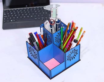 May include: A blue wooden desk organizer with four compartments. The organizer has a decorative laser cut design and is filled with pens, pencils, and markers.