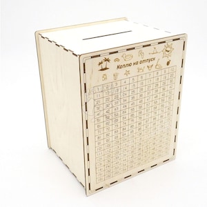 May include: A wooden piggy bank with a slot on the top. The front of the bank has a grid of numbers from 1 to 160 and the text "Коплю на отпуск" which translates to "Saving for vacation".