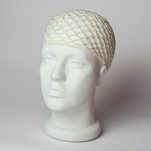 May include: A white wig cap made of a net-like material is displayed on a white mannequin head. The cap has a diamond pattern and covers the top of the head. The mannequin head is smooth and has a neutral expression.