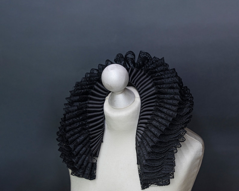 May include: A black lace and satin ruffled collar on a white mannequin.