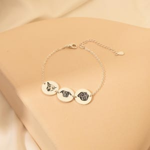 Puede incluir: Pulsera de plata con tres dijes redondos con retratos de perros grabados.