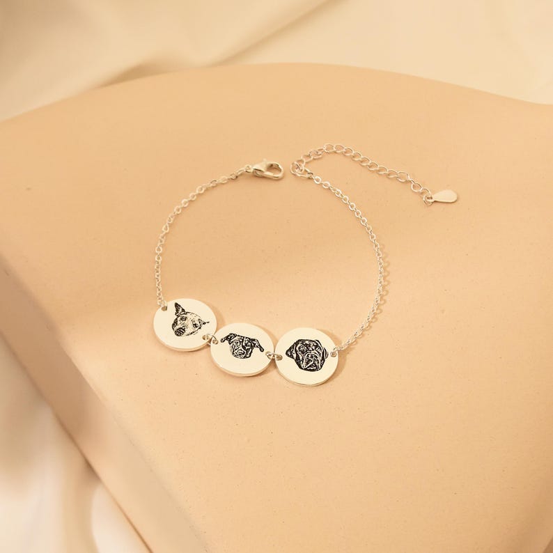 Puede incluir: Pulsera de plata con tres dijes redondos con retratos de perros grabados.